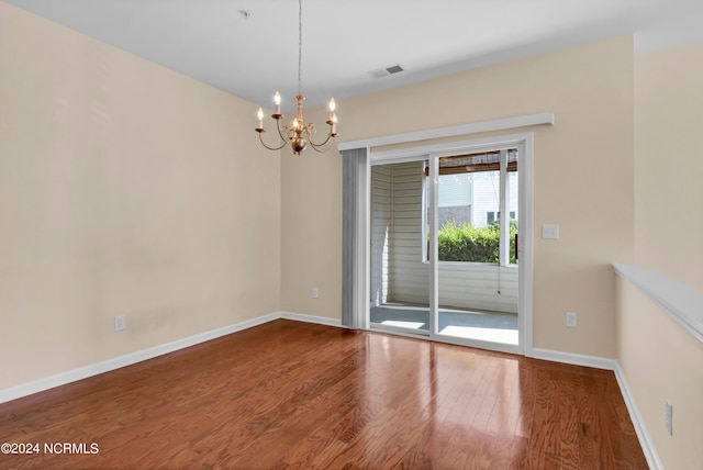 spare room featuring a chandelier and wood-type flooring