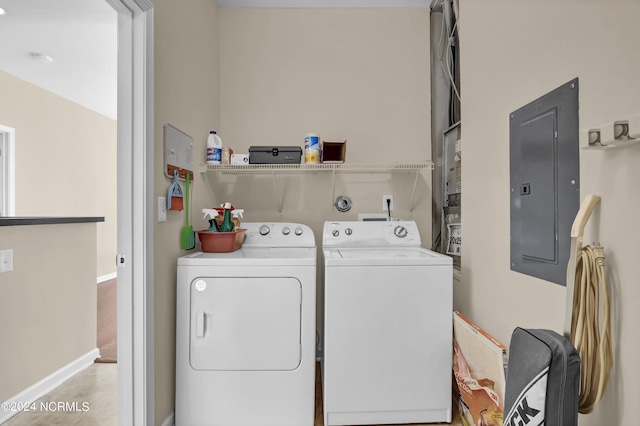laundry room with laundry area, baseboards, washing machine and dryer, and electric panel