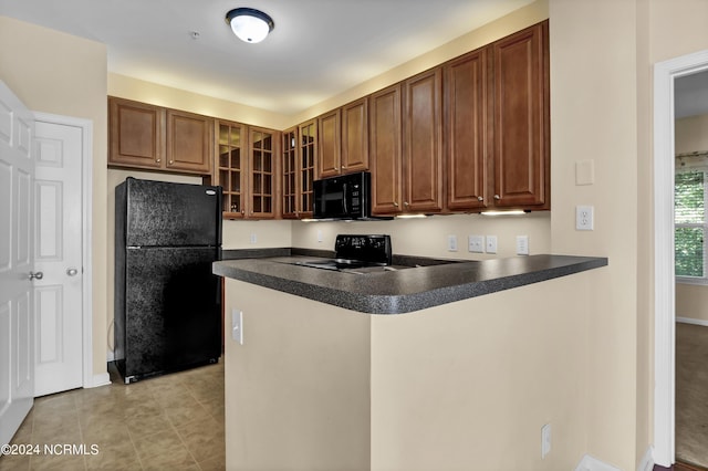 kitchen featuring a peninsula, light tile patterned flooring, dark countertops, glass insert cabinets, and black appliances
