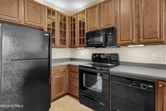 kitchen with glass insert cabinets, dark countertops, black appliances, and brown cabinets