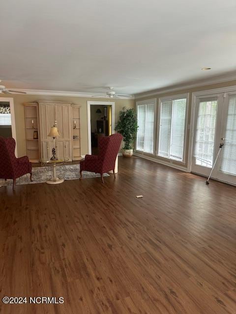 unfurnished living room featuring ornamental molding, ceiling fan, and dark wood-type flooring