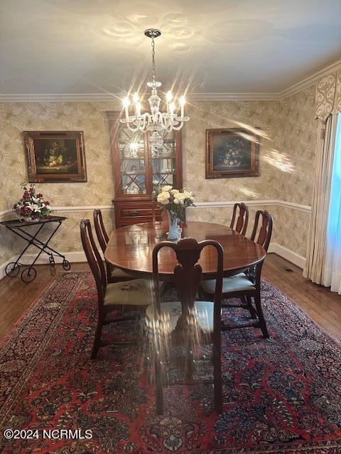 dining area featuring ornamental molding, a chandelier, and hardwood / wood-style floors