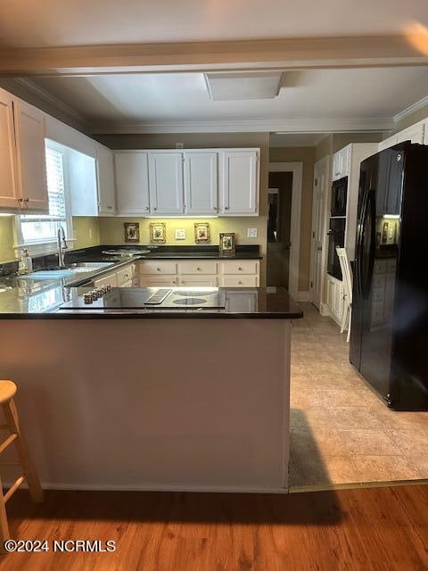 kitchen featuring white cabinets, black appliances, kitchen peninsula, and light wood-type flooring