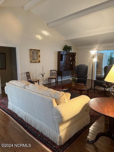 living room with vaulted ceiling with beams and dark wood-type flooring