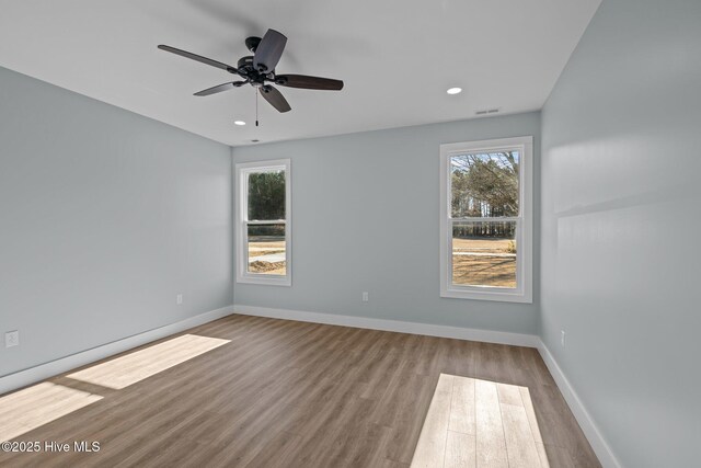 unfurnished room featuring a wealth of natural light, ceiling fan, and light wood-type flooring