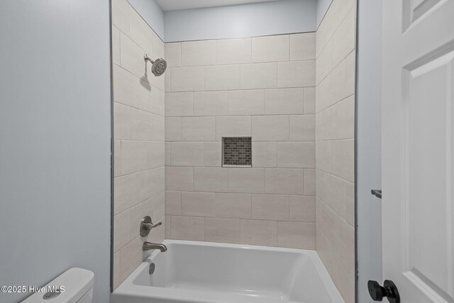 bathroom featuring toilet and tiled shower / bath