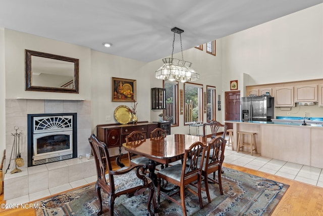 dining room featuring light hardwood / wood-style flooring, a tiled fireplace, and a chandelier