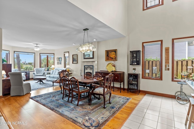 114 SW 21st St, Oak Island, NC 28465 - dining area with baseboards, a tiled fireplace, ceiling fan with notable chandelier, and light wood finished floors