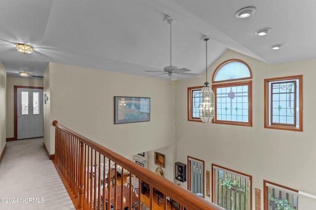 hallway featuring light colored carpet, a chandelier, and vaulted ceiling