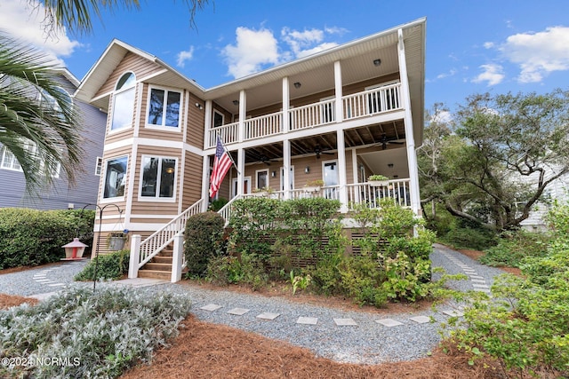 114 SW 21st St, Oak Island, NC 28465 - view of front of house featuring covered porch, stairway, a balcony, and a ceiling fan
