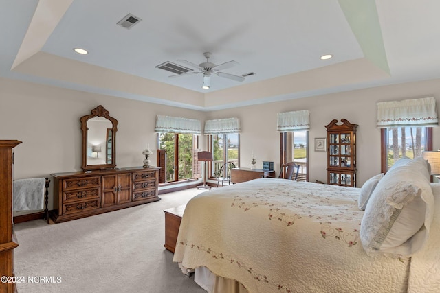 carpeted bedroom with a tray ceiling and ceiling fan