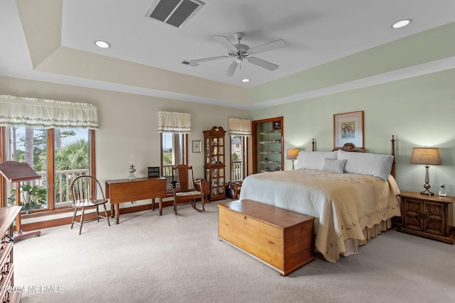 carpeted bedroom with ceiling fan and a tray ceiling