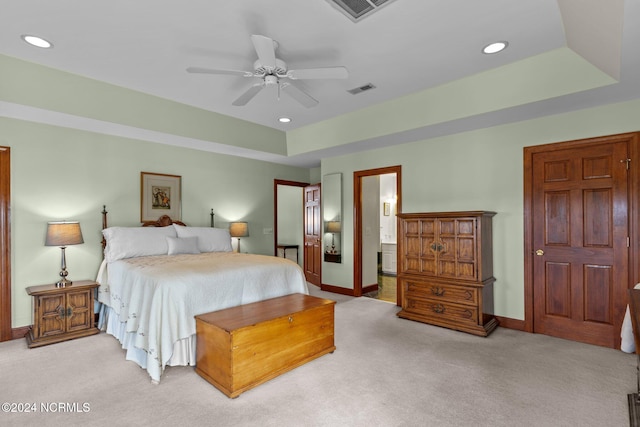 carpeted bedroom featuring ceiling fan, ensuite bath, and a tray ceiling