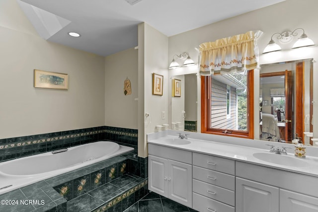 bathroom with tiled tub, vanity, and tile patterned flooring