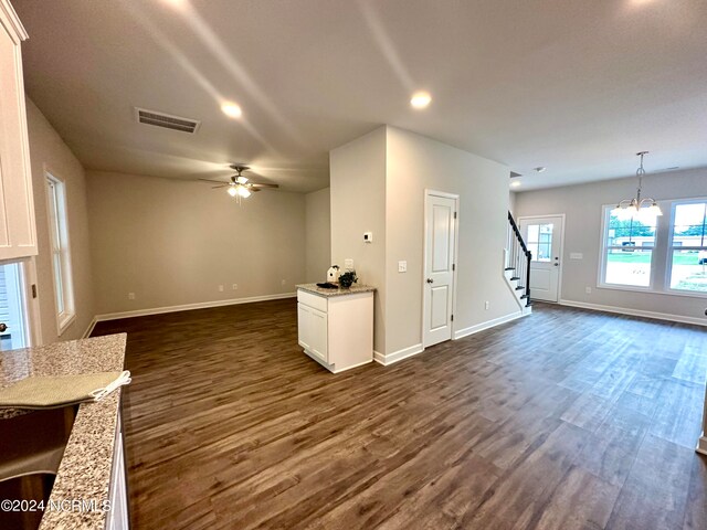 unfurnished living room with sink, ceiling fan with notable chandelier, and dark hardwood / wood-style floors