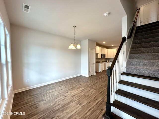 stairs with hardwood / wood-style flooring and an inviting chandelier