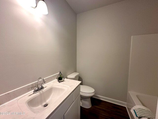 bathroom featuring vanity, hardwood / wood-style floors, toilet, and a bathing tub