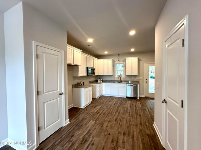 kitchen with sink, dark wood-type flooring, stainless steel appliances, white cabinets, and decorative light fixtures