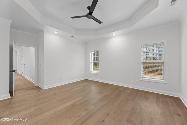 spare room featuring a tray ceiling, light hardwood / wood-style flooring, ceiling fan, and crown molding