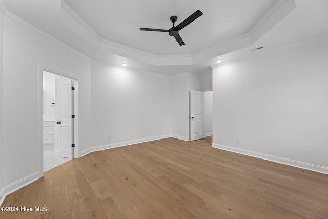 spare room featuring light hardwood / wood-style flooring, a raised ceiling, ceiling fan, and ornamental molding