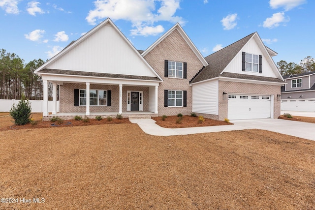 view of front of property with covered porch, a garage, and a front lawn