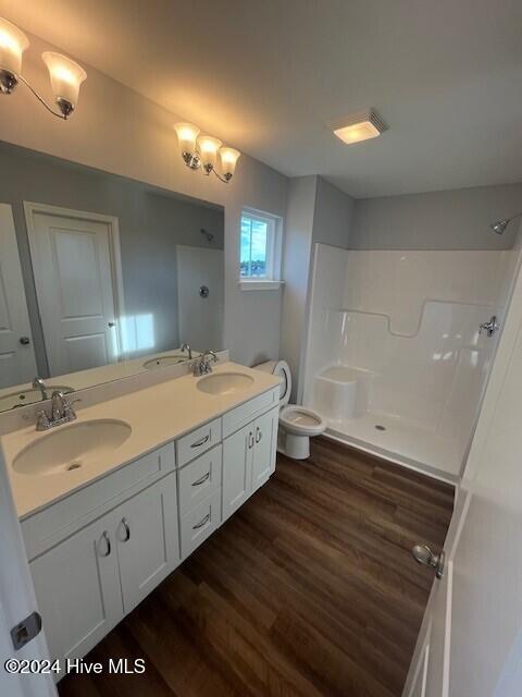 bathroom with a shower, vanity, wood-type flooring, and toilet