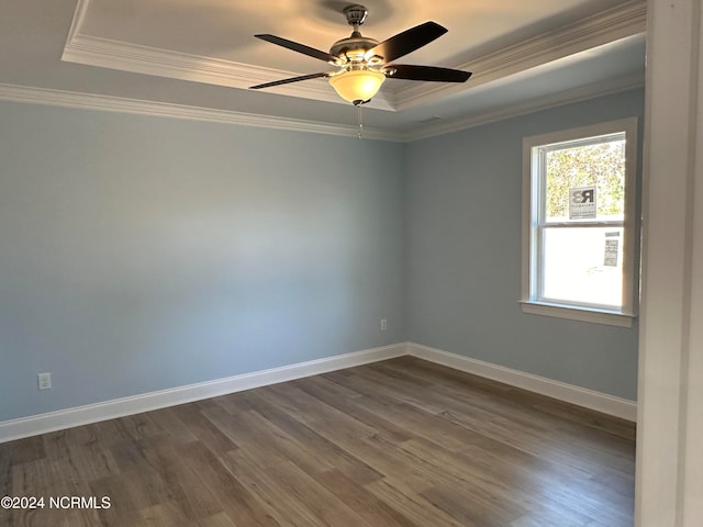 spare room featuring ornamental molding, a tray ceiling, dark wood-type flooring, and ceiling fan