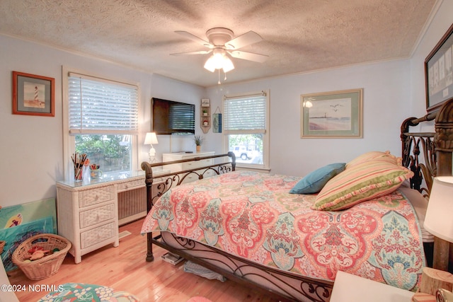 bedroom featuring ceiling fan, crown molding, a textured ceiling, and light hardwood / wood-style flooring