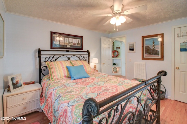 bedroom featuring light hardwood / wood-style flooring, a textured ceiling, crown molding, and ceiling fan