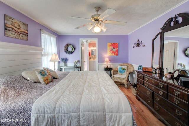 bedroom featuring ceiling fan, a textured ceiling, light wood-type flooring, ornamental molding, and ensuite bathroom