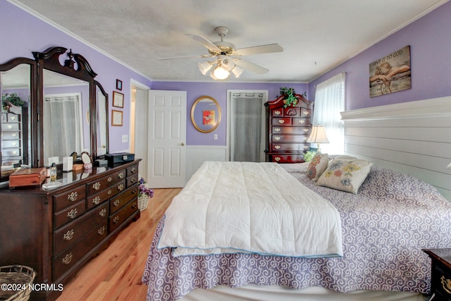 bedroom featuring light hardwood / wood-style floors, ornamental molding, a textured ceiling, and ceiling fan