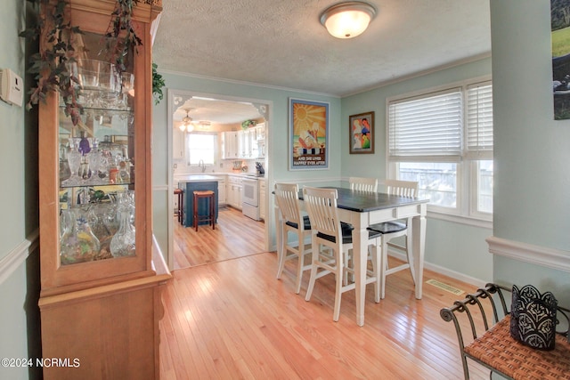 dining area with light hardwood / wood-style flooring, plenty of natural light, and crown molding