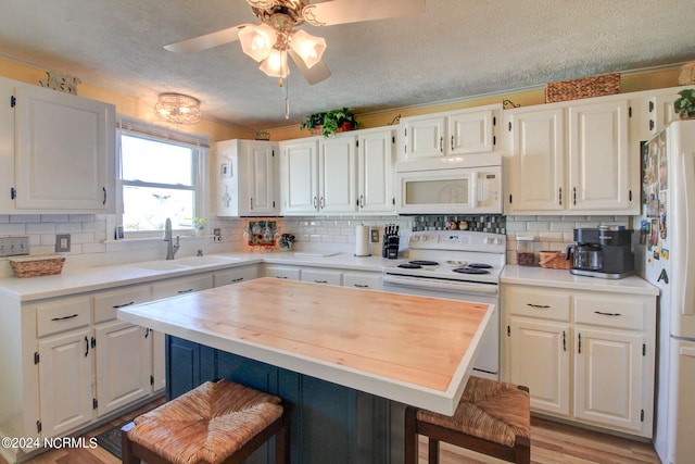 kitchen featuring light hardwood / wood-style floors, a breakfast bar, white cabinetry, a textured ceiling, and white appliances