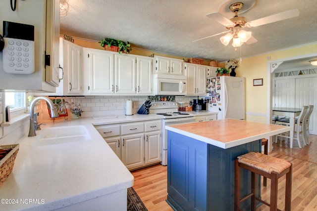 kitchen with light hardwood / wood-style flooring, sink, a center island, white cabinets, and white appliances