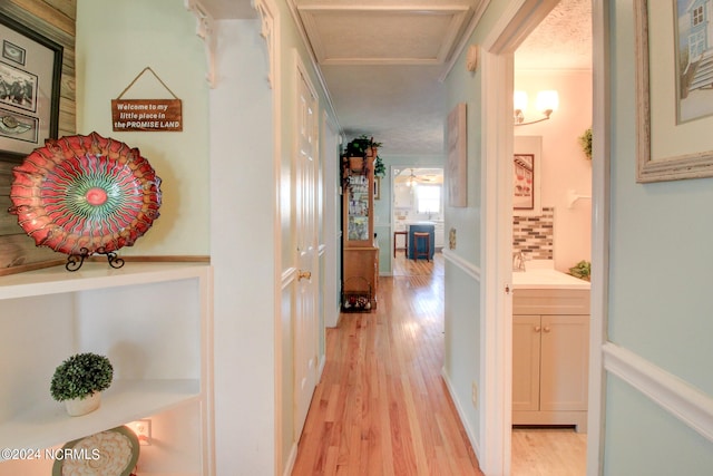 hall featuring light hardwood / wood-style floors, ornamental molding, and a textured ceiling