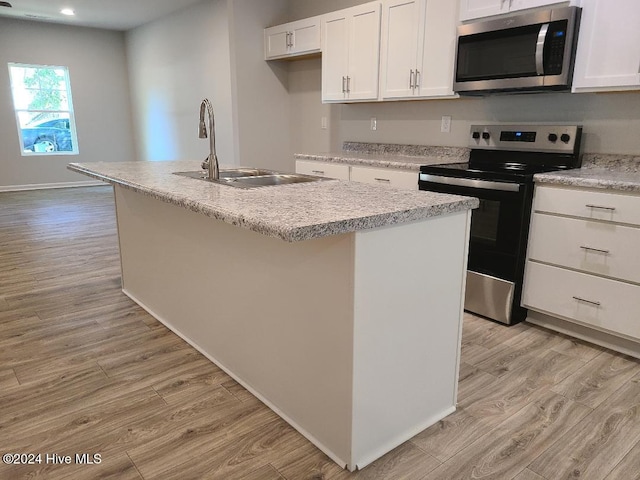 kitchen with stainless steel appliances, sink, light hardwood / wood-style flooring, white cabinetry, and an island with sink