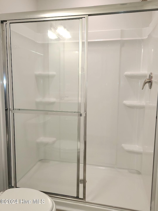 bathroom with toilet and a shower with shower door