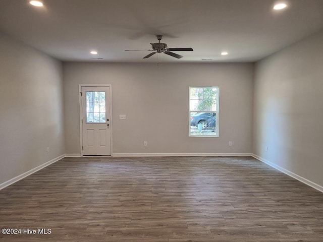 empty room featuring ceiling fan, a healthy amount of sunlight, and dark wood-type flooring