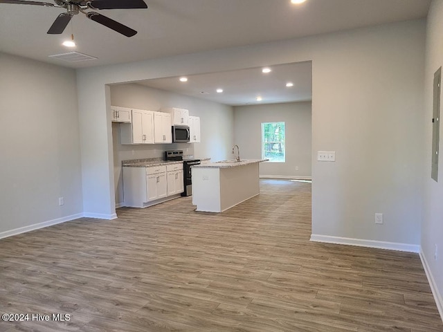 kitchen with light hardwood / wood-style floors, white cabinetry, a kitchen island with sink, and appliances with stainless steel finishes