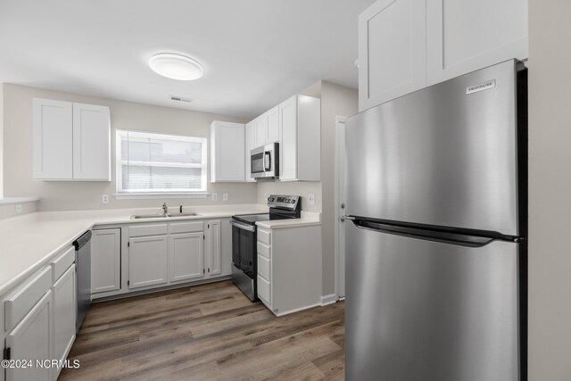 kitchen featuring dark hardwood / wood-style flooring, white cabinets, appliances with stainless steel finishes, and sink