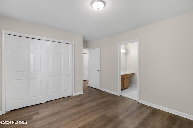 unfurnished bedroom featuring light wood-type flooring, connected bathroom, and a closet