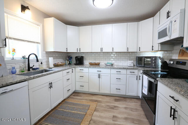 kitchen featuring white appliances, white cabinetry, tasteful backsplash, and sink