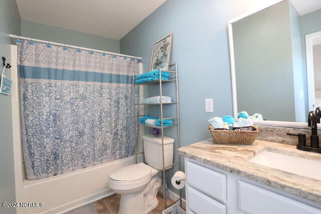 full bathroom featuring shower / bathtub combination with curtain, hardwood / wood-style floors, vanity, and toilet