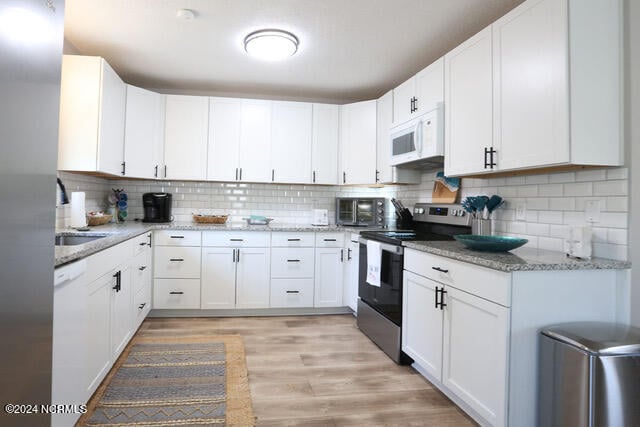 kitchen with light hardwood / wood-style floors, white cabinets, white appliances, backsplash, and light stone countertops