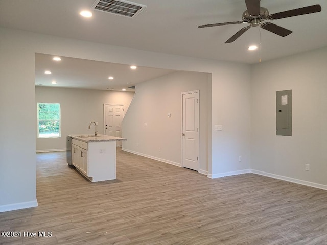 kitchen with a center island with sink, white cabinets, electric panel, and light hardwood / wood-style flooring