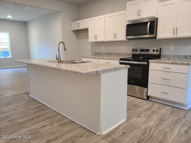 kitchen featuring stainless steel appliances, sink, light hardwood / wood-style flooring, white cabinets, and an island with sink