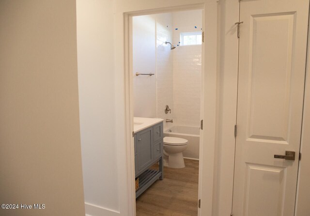 full bathroom with hardwood / wood-style floors, tiled shower / bath combo, toilet, and vanity