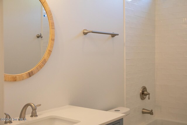 full bathroom with vanity, tiled shower / bath combo, and toilet