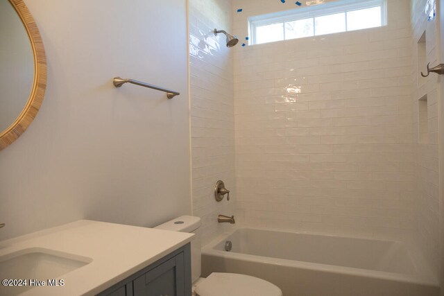 full bathroom featuring vanity, tiled shower / bath, and toilet