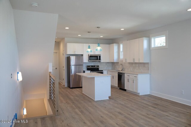 kitchen featuring hanging light fixtures, a kitchen island, light hardwood / wood-style floors, white cabinetry, and stainless steel appliances